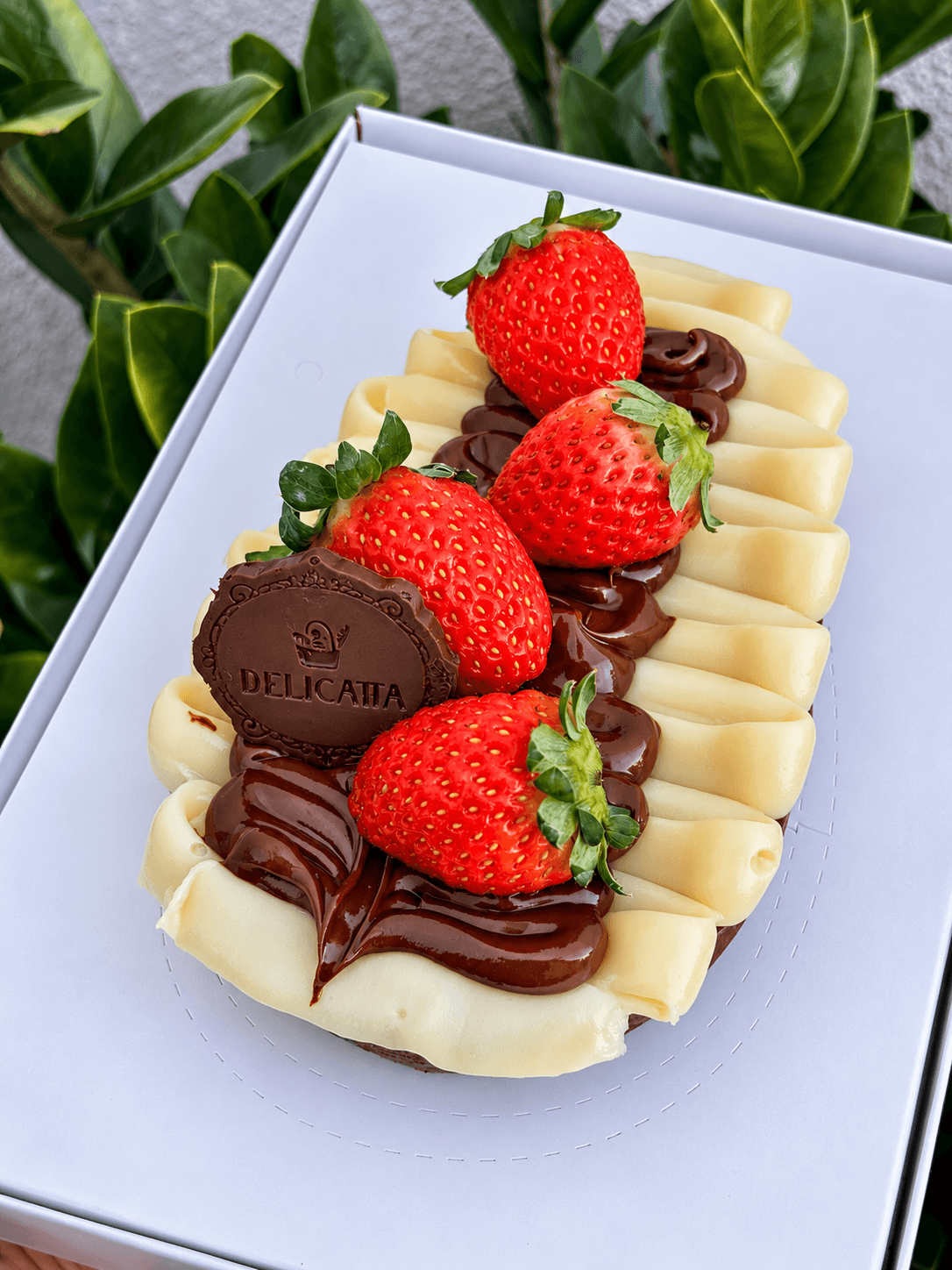 Ovo de colher com creme de ninho, nutella e morangos, na caixa branca da Delicatta