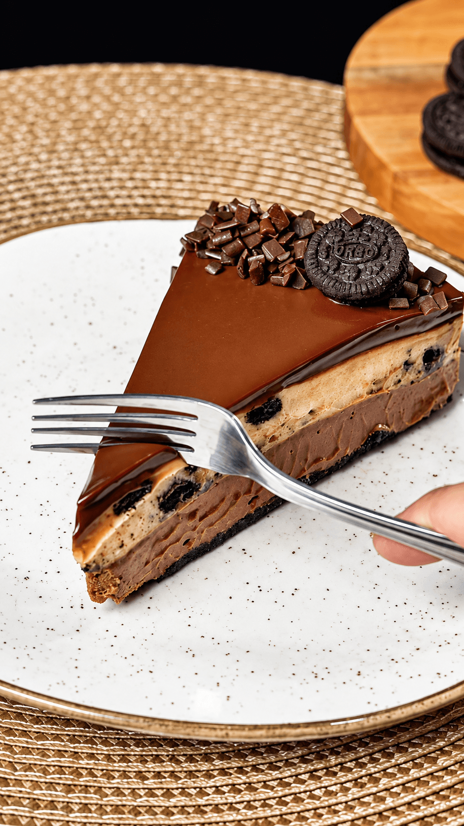 Fatia de torta de brownie em camadas, coberta com ganache brilhante e biscoito de chocolate