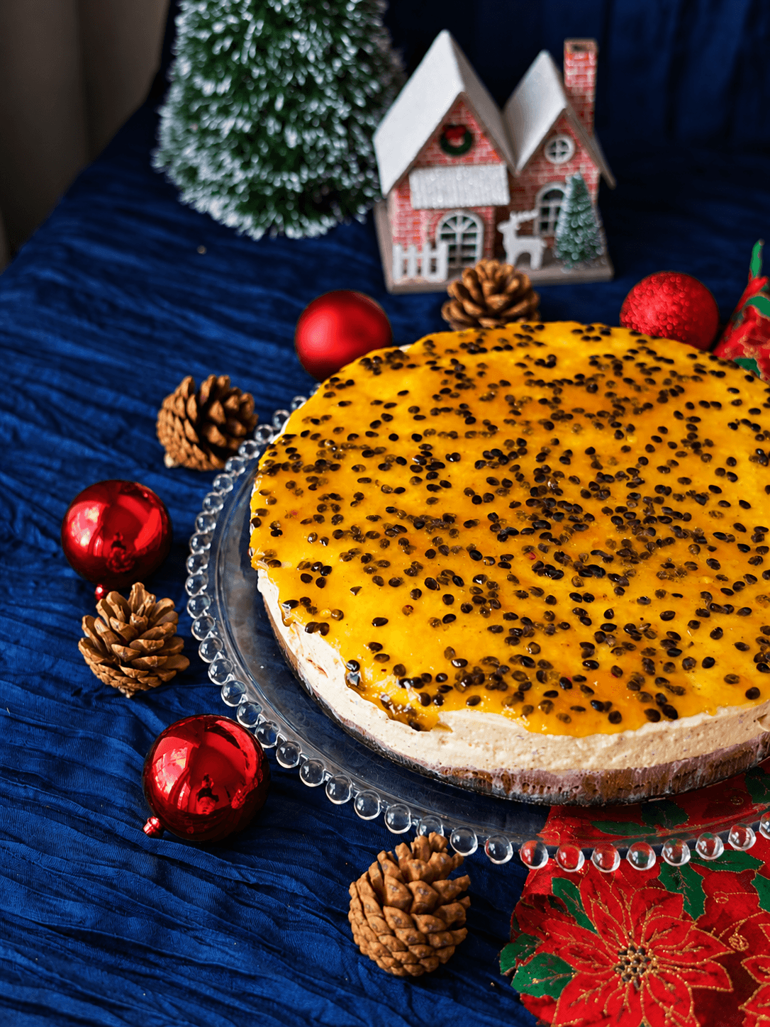 Torta de maracujá inteira sobre prato de vidro, coberta com calda e sementes da fruta